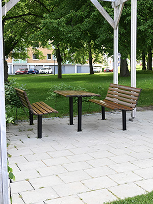 Wooden park table and park benches placed in a communal park along a path.